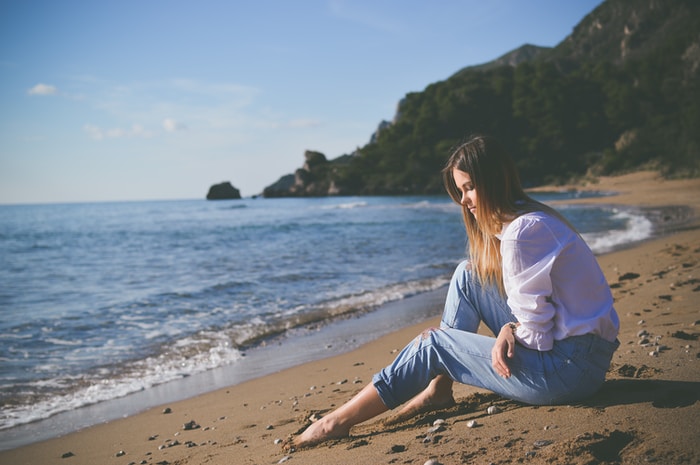 woman sitting on beach shore during daytime